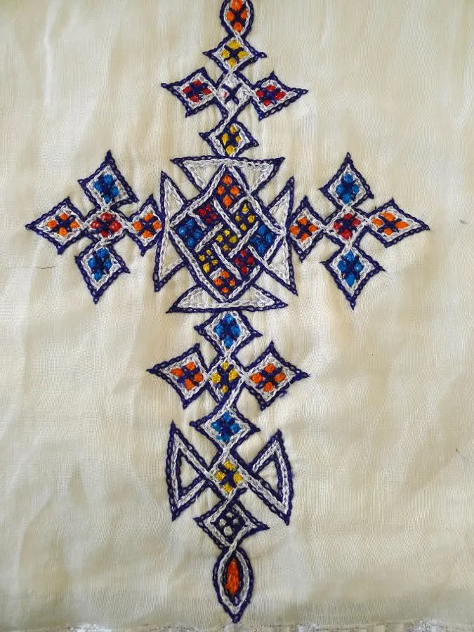 White, long sleeved traditional Ethiopian dress with blue and red cross embroidered motif